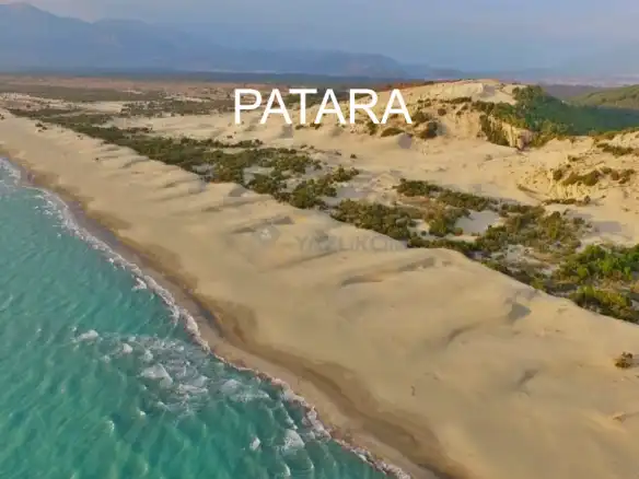 Ülkenin en güzel plajlarına sahip, turizm cenneti, doğal güzellikler destinasyonu bölgeleri neresi diye sorulsa Antalya cevapların en başında gelir. Plajları, tarihi ve kültürel zenginlikleri, deniz ısısı bile Antalya’yı gözde tatil bölgelerinden biri haline getirmek için yeterli. Tabi ülkenin en uzun 2. Dünyanın ise 11. kumsalı olma özelliğini elinde barındıran Patara Plajı’nın da bölgede olduğunu düşünürsek, Antalya’nın tatil bölgeleri arasındaki önemi ve yeri daha da anlam kazanıyorsanki, sizce de öyle değil mi? Türkiye’nin Samandağ Plajından sonra en uzun ikinci plajı olan Patara Plajı, 12 km uzunluk ve 250 ila 1500 metre genişliğe sahip olup, derinliği 300 metre civarındadır. Diğer plajlara nazaran suyu sığ olan Patara plajının yıllık ziyaretçi oranı neredeyse 400 – 500 bin civarında. Doğal bir güzellik olması yanında güvenli bir yer olması da bölgenin tercih edilmesinde önemli bir etken. Tatil yaparken dinlenmek, dinlenirken bolca temiz hava almak, temiz hava alırken güneşin teninizdeki aksini hissetmek istiyorsanız Patara Plajını mutlaka ziyaret edilecek yerler arasında baş sıraya çıkartın. Uzunca bir kuraklık ve susuzluktan sonra karşınıza çıkan devasa bir vaha gibi, uçsuz bucaksız ve göz kamaştıran. Tabi ne yazık ki nesli tükenme tehlikesiyle karşı karşıya olan CarettaCaretta’ların da üreme merkezi olduğunu düşünürsek Patara Plajı, hem cazibeli hem özel bir hal alıyor ziyaretçiler için. Plajın bu özellikleri nedeniyle koruma altında olduğunu belirtmekte de fayda var. Bir yere ilk kez gidilecekse güzel ve doğal olmasına özellikle dikkat edilir. Ancak göz ardı edilmeyecek olan diğer önemli bir hususda güvenli bir yer olması. Patara plajının tercih etmek için doğal bir doğa mucizesi olması yanında yerli ve yabancı ziyaretçiler için ayrıca güvenli bir yer olması dikkat çeken en önemli özelliklerinden. Akdeniz’in en güzel kumsal ve sahillerinden biri Patara Plajı evet, çünkü göz alabildiğine uzanan engin bir deniz, yine göz alabildiğine uzanan engin bir kumsal ve ortasında yüzünüzü okşayan hafif meltem esintisinin huzurunuza eşlik ettiği dinginlikte siz. Plajın rüzgar alıyor olması, güneşin etkilerini bir nebze olsun azaltması yanında, sörf tutkunları için de elverişli bir uğrak nokta. Patara Plajı’nın tüm bu özellikleri sadece yaz ve deniz turizmi için cazibe noktasına haline getiriyor gibi görünse de adını Patara Antik Kent’inden aldığını düşünürsek, tarihi ve kültürel anlamda da Patara dikkatleri üzerine çeken bir lokasyon. Kültürel, doğal güzellik, tarihi doku, carettacarettalar… Tercihiniz her ne olursa olsun, Patara’dan eliniz boş ayrılmayacaksınız.Plajın Yeşilçam filmlerinde kullanılan doğal bir çöl seti olduğunu da notlarımıza eklemekte fayda var. Plaja giriş ücretli olup ( cüzi bir miktar ), plaj içinde bulunan kafeteryadan alışveriş yapabilir aynı zamanda şemsiye ve şezlong ihtiyacınızı da karşılayabilirsiniz.