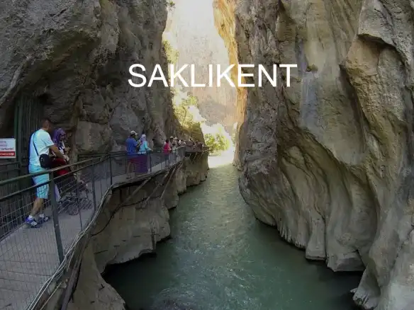 Saklıkent Muğla’nın incilerinden Fethiye ve Fethiye’nin incisi Saklıkent Kanyonu ismiyle müsemma saklı bir kent saklı bir cennet. Ülkenin çoğu kıyı kesimi yaz turizmi ile gözde destinasyonlar ancak bazen şehir yorgunluğunu atmak için daha sessiz, sakin, denizden bir nebze uzaklaşıp doğayla baş başa kalmak isteriz ya işte Saklıkent bu anlamda fazlasıyla sizleri tatmin edecek bir yer. Saklıkent, Antalya sınırında bulunan toplam uzunluğu 18 km, yüksekliği 200 ila 600 metre arasında değişen, görenleri etkilemekle kalmayıp ülkemizin doğal güzelliklerine bir kez daha hayranlıkla şahit olacağımız bir doğa harikası. Nasıl meydana geldiği tam olarak bilinmese de, bundan binlerce yıl önce dünyada meydana gelen jeolojik patlama sonucu ortaya çıktığı bilinmektedir. Kanyonun bu kadar büyük olmasına rağmen, 2 metreye kadar daralan yerlerde gökyüzünü görmek neredeyse imkansız. Ancak bulunduğunuz kanyon buz gibi suları, kayaların devasa büyüklüğüne dalıp gittiğinizden gökyüzünü görememeyi çok da dert etmiyorsunuz. Saklıkent, konuklarının gönül rahatlığıyla ziyaretlerini yapabilmeleri aynı zamanda bu doğa harikası alanı tehlikeden uzak bir şekilde gezebilmeleri için merdiven ve köprülerle çevrili. Fethiye’nin Ölüdeniz’den sonra en fazla ziyaretçi ağırladığı yerlerden olan Saklıkent, çok değil bundan 26 yıl önce keşfedilmiş. Kanyonun en güzel özelliklerinden biri, el değmemiş olması. Adı üstünde doğal bir alan. Üzerinde yörenin örneklerinden kilimler ile çevrilmiş, yemeğinizi yerken ayaklarınız buz gibi su içinde soğutup, bol bol oksijen soluyabileceğiniz mekanlarla çevrili. Ancak bu mekanlar Saklıkent’in güzelliğini bozmuyor tam tersi ayrı ve renkli bir hava katıyor bu milli parka. Gezmeyi sevenler bilir, ülkenin çoğu kıyı bölgesi tadı dimağlarda iz bırakan gözlemeleri ile meşhur. Saklıkent’e giderken yol üstünde pek çok gözlemeci ile karşılaşıyorsunuz ve kanyona vardığınızda da yine mis gibi kokularıyla sizleri çeşitli gözlemeci karşılıyor. Yani kanyon her anlamda beklentilerinizi karşılayacak bir gezi sunuyor sizlere. Saklıkent’in özelliği, kayaların arasında olması ve bu özellik elbette içi büyüklü küçüklü suların içinde yürürken size zorluk yaratmaması için düz bir ayakkabı tercih etmeniz gerekmektedir. Ancak ayakkabınız çok uygun değilse bile merak etmeyin, kanyonda gezmeniz için size uygun ayakkabılardan kiralayıp serin suların ve bu gösterişli kayaların tadını çıkarabilirsiniz. Ha tabi unutmadan yanınıza yedek bir kıyafet almanızda fayda var. Çünkü Islanmanız ya da sularda yürürken kendiniz serin sulara bırakmanız olası bir ihtimal. Fethiye’ye gidenler bilir, yazın sıcaklık bazı dönemlerde 40 dereceye kadar ulaşabiliyor. Ancak bu kavurucu sıcağı Saklıkent içinde hissetmiyor tam tersi ayağınızı soğutan buz gibi sularla dışarıdaki sıcaklığın sizi bunaltmasına izin vermiyor bu güzide destinasyon. Tabi bu cennet köşeyi ziyaret belirli bir ücret karşılığında kapılarını size açıyor. Sivil 6 TL öğrenci için de 3 TL gibi bir fiyat ile kanyonu ziyaret edebilirsiniz.
